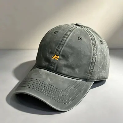 A gray-green baseball cap with a small orange embroidered logo on the front, photographed on a white surface.