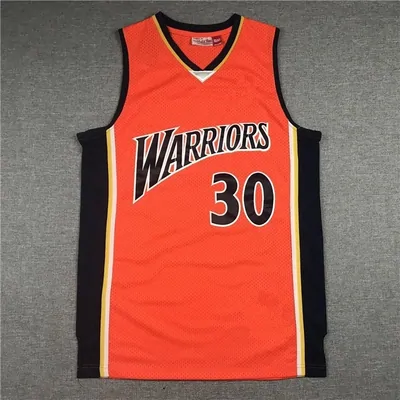 An orange Golden State Warriors basketball jersey, number 30, laid flat on a pale surface.