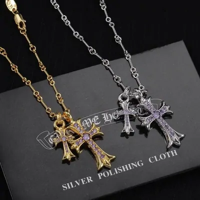Two cross pendants on chains, one gold and one silver, set with small stones and lying on a black polishing cloth.
