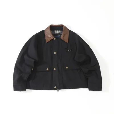 A black jacket with a brown leather collar and brass snap buttons, laid flat on white, with a checked lining showing at the neck.