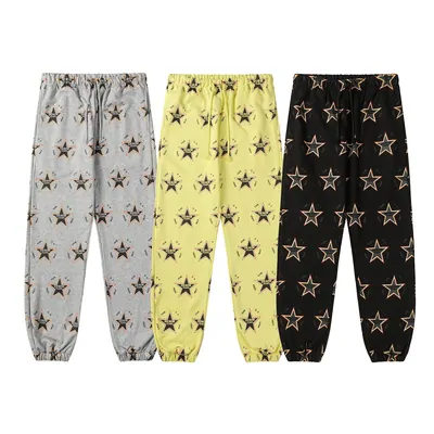 Three pairs of star-print joggers laid side by side in gray, yellow and black.
