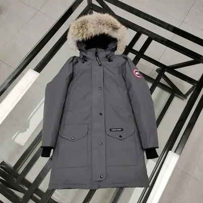 A gray Canada Goose parka with a fur-trimmed hood, hanging from a metal rail.